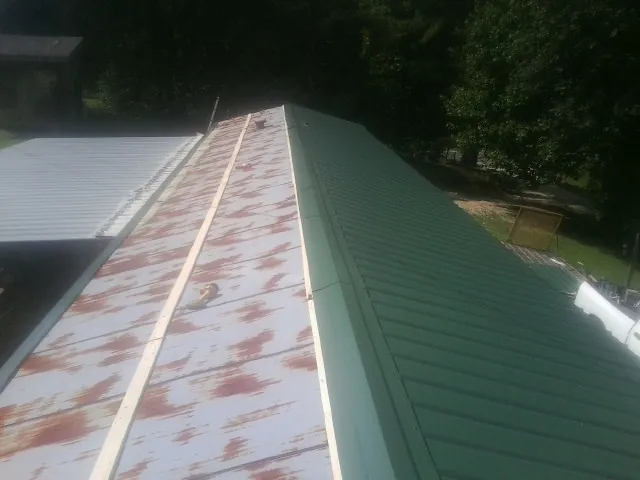 Old rusted panels beside newly installed green metal roofing — Wind Damage Roof Repair by Roofing Brothers in Cedarpines Park