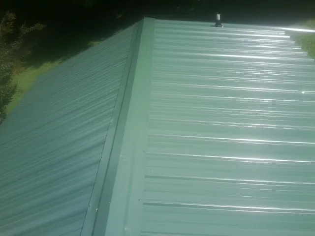 New green metal panels meeting at the ridge of a roof — Flat Roof Repair work by our crew in Cedarpines Park