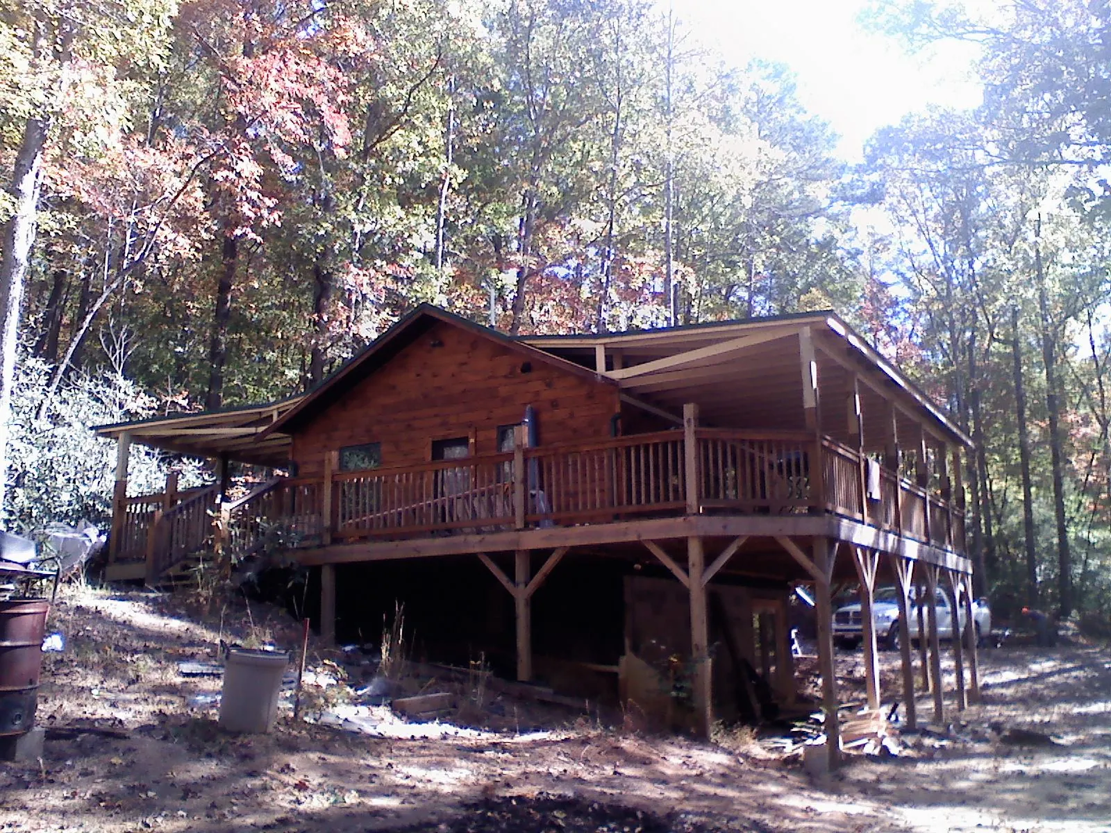 Log cabin with a wraparound porch and metal roof in the fall in Cedarpines Park