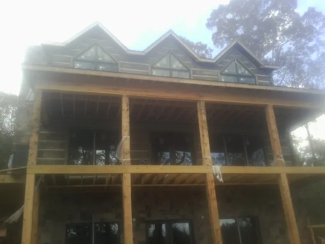 Dormers and porch framing on a large log home under construction — Roof Coating work by our crew in Cedarpines Park