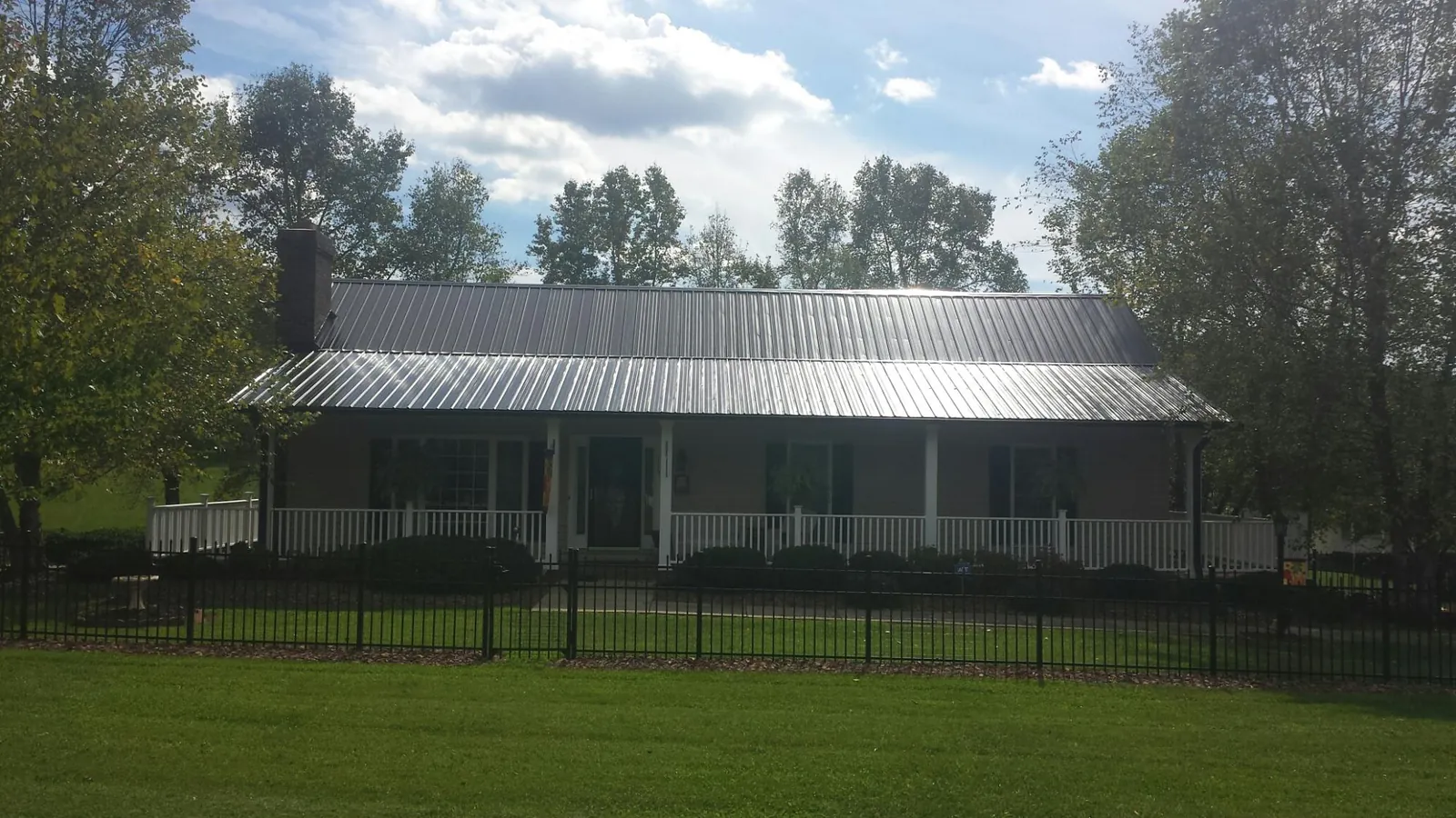 Gray metal roof on a brick ranch with a full width front porch — Gutter Guard Installation work by our crew in Cedarpines Park