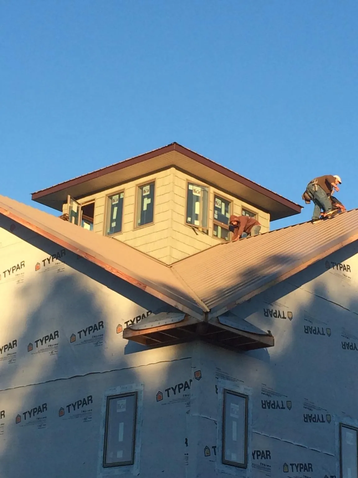 Roofers working around a rooftop cupola on a new metal roof at sunset — Roof Waterproofing in Cedarpines Park by Roofing Brothers